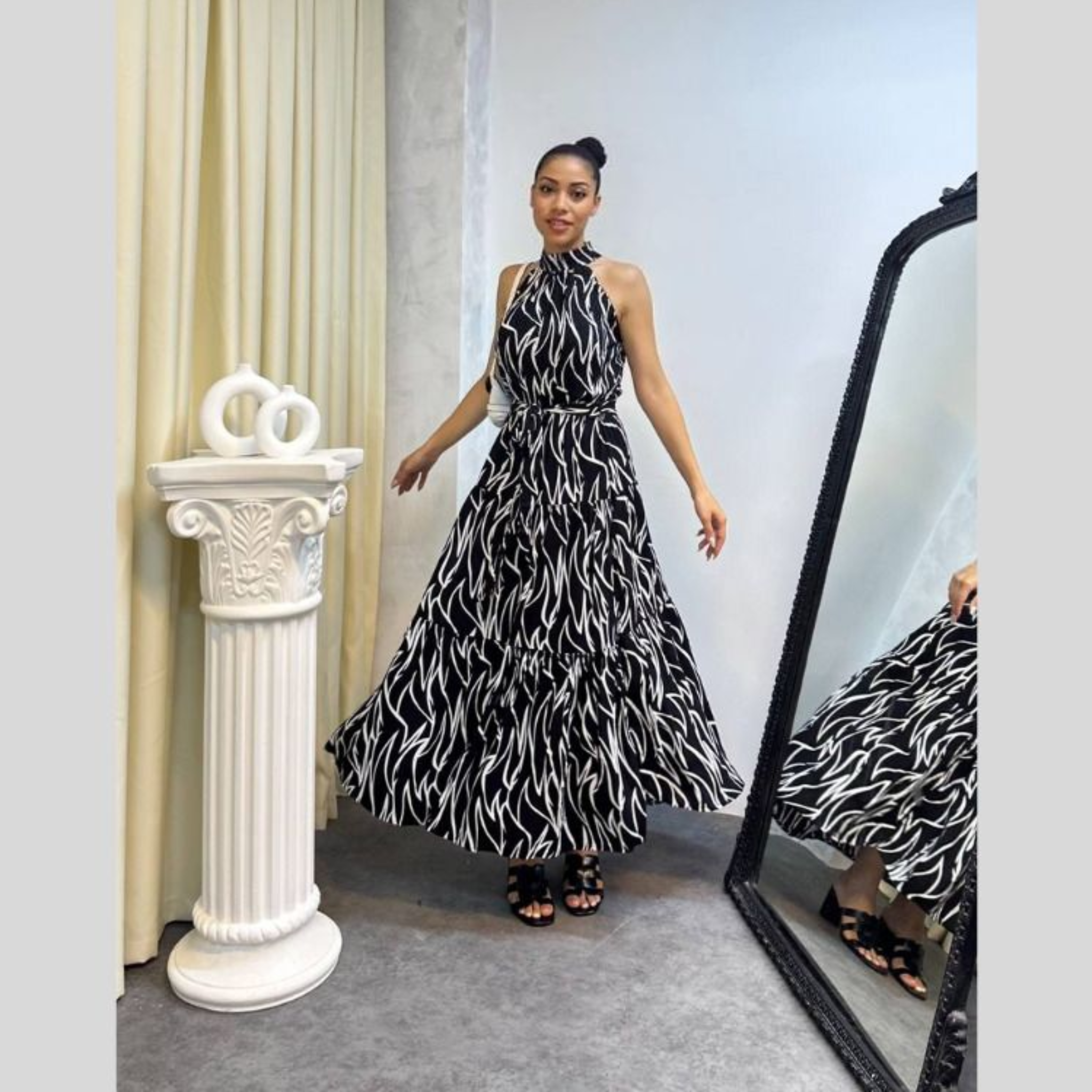 Woman in a black and white patterned dress standing in front of a mirror.