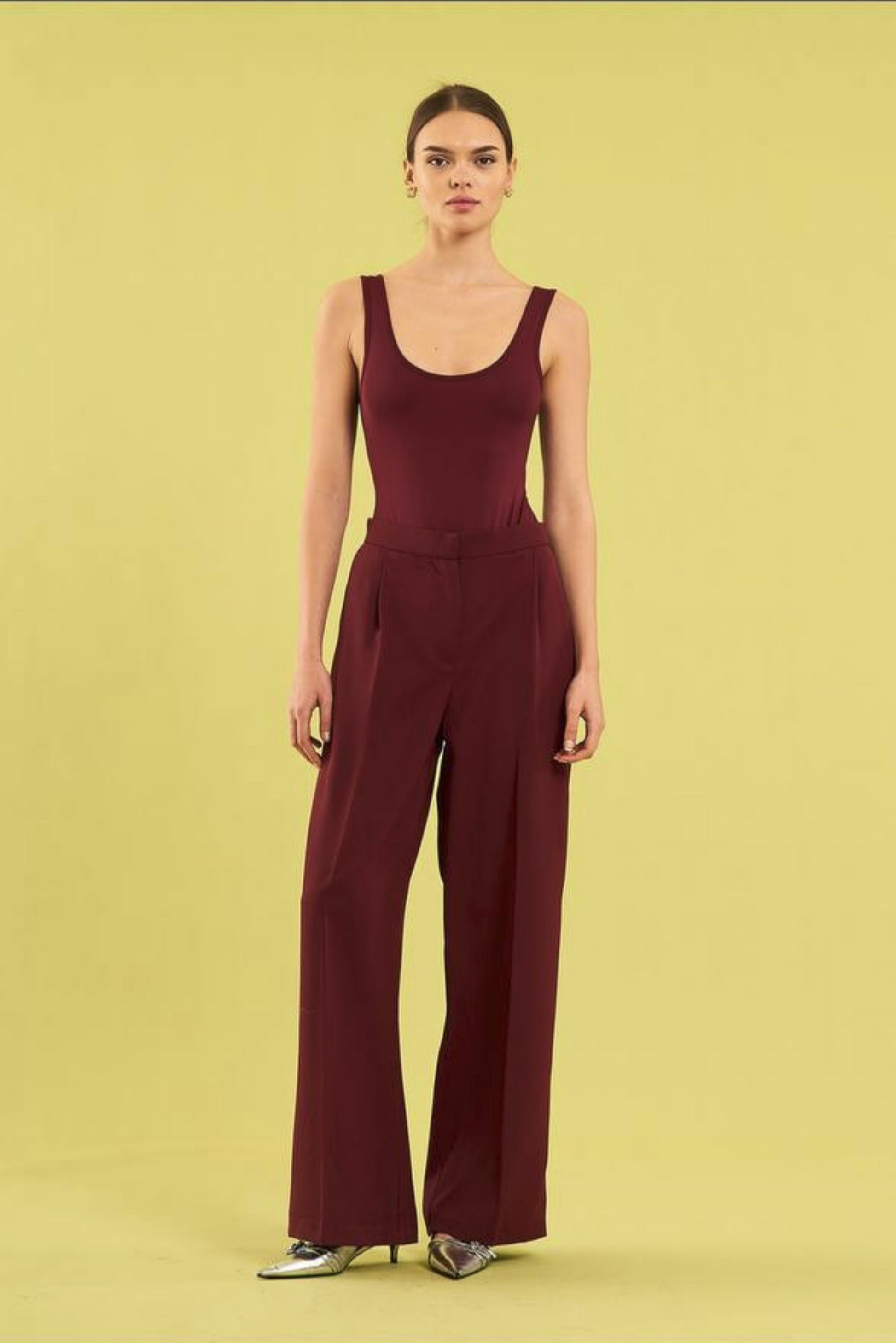Woman wearing a burgundy jumpsuit on a yellow background