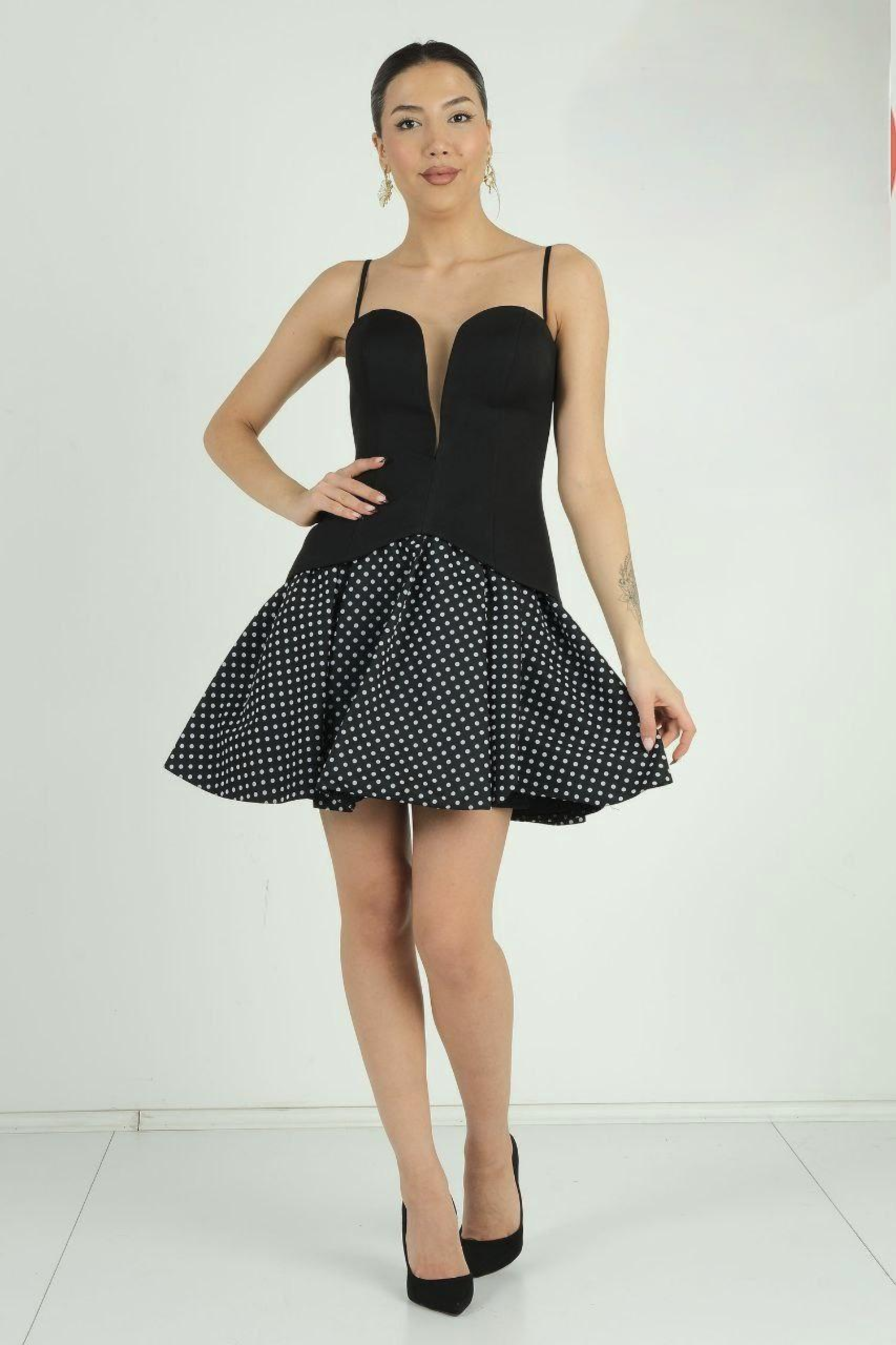 Woman wearing a black dress with a polka dot skirt on a white background