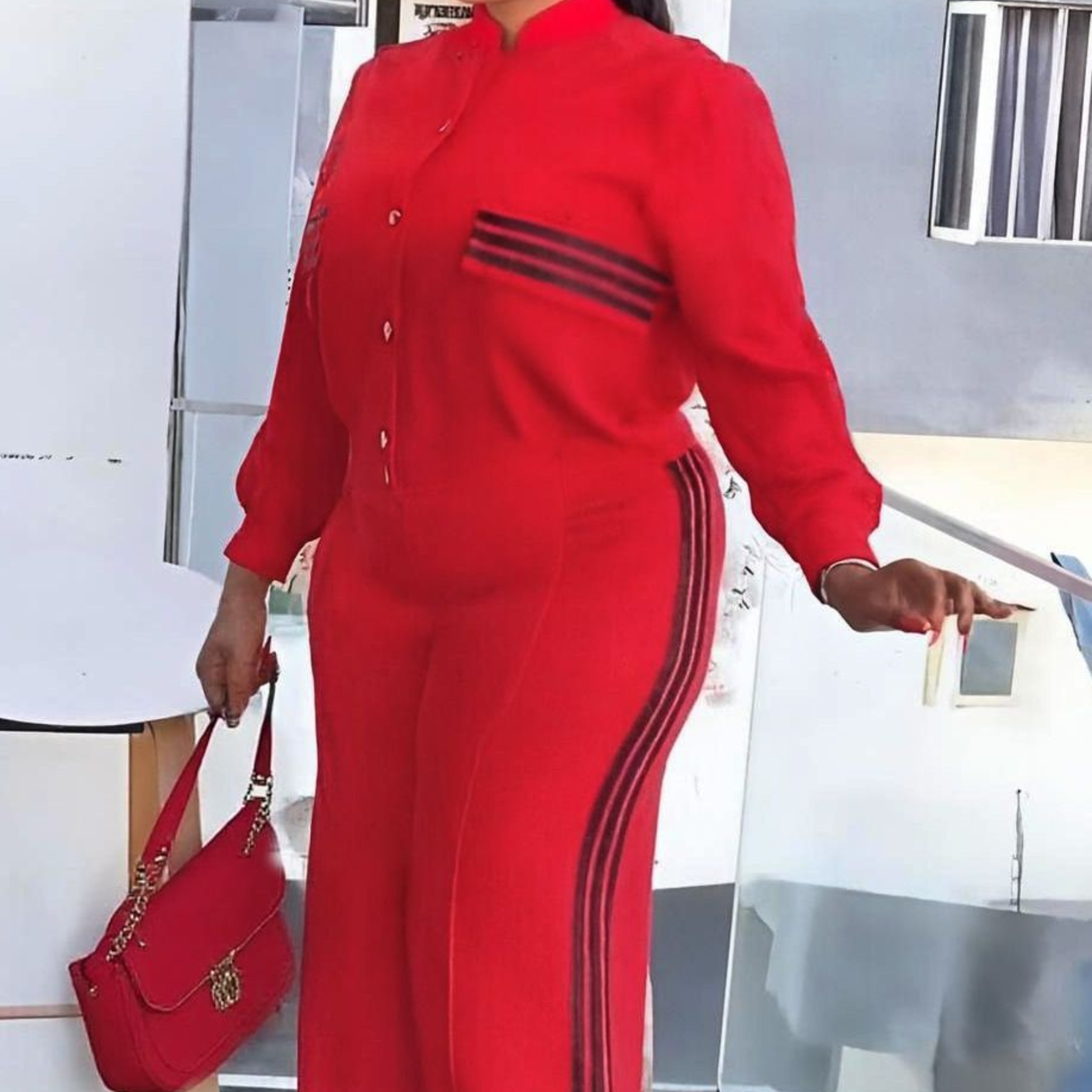 Woman in a red outfit with black stripes standing outdoors.