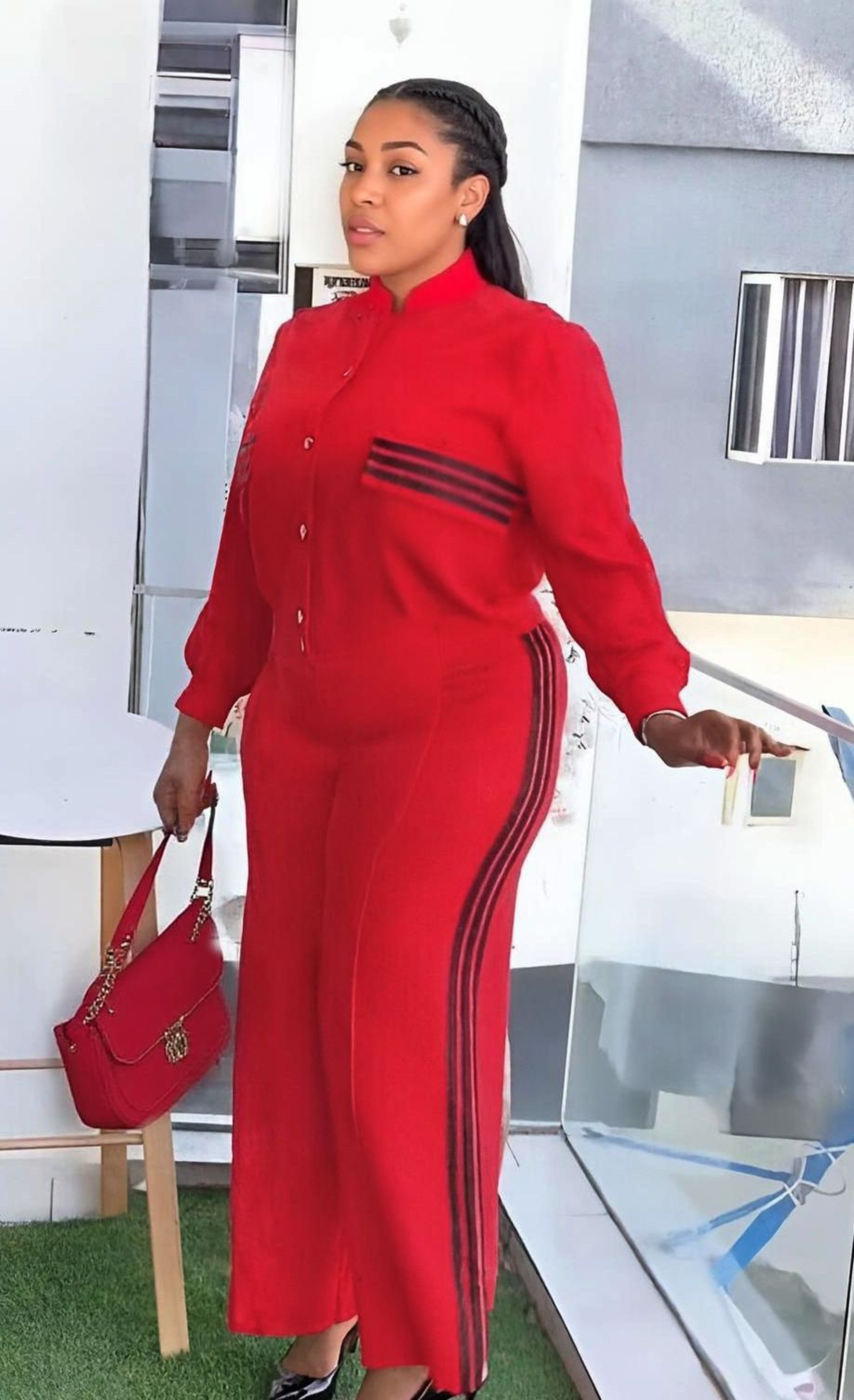 Woman in a red outfit with black stripes standing outdoors.