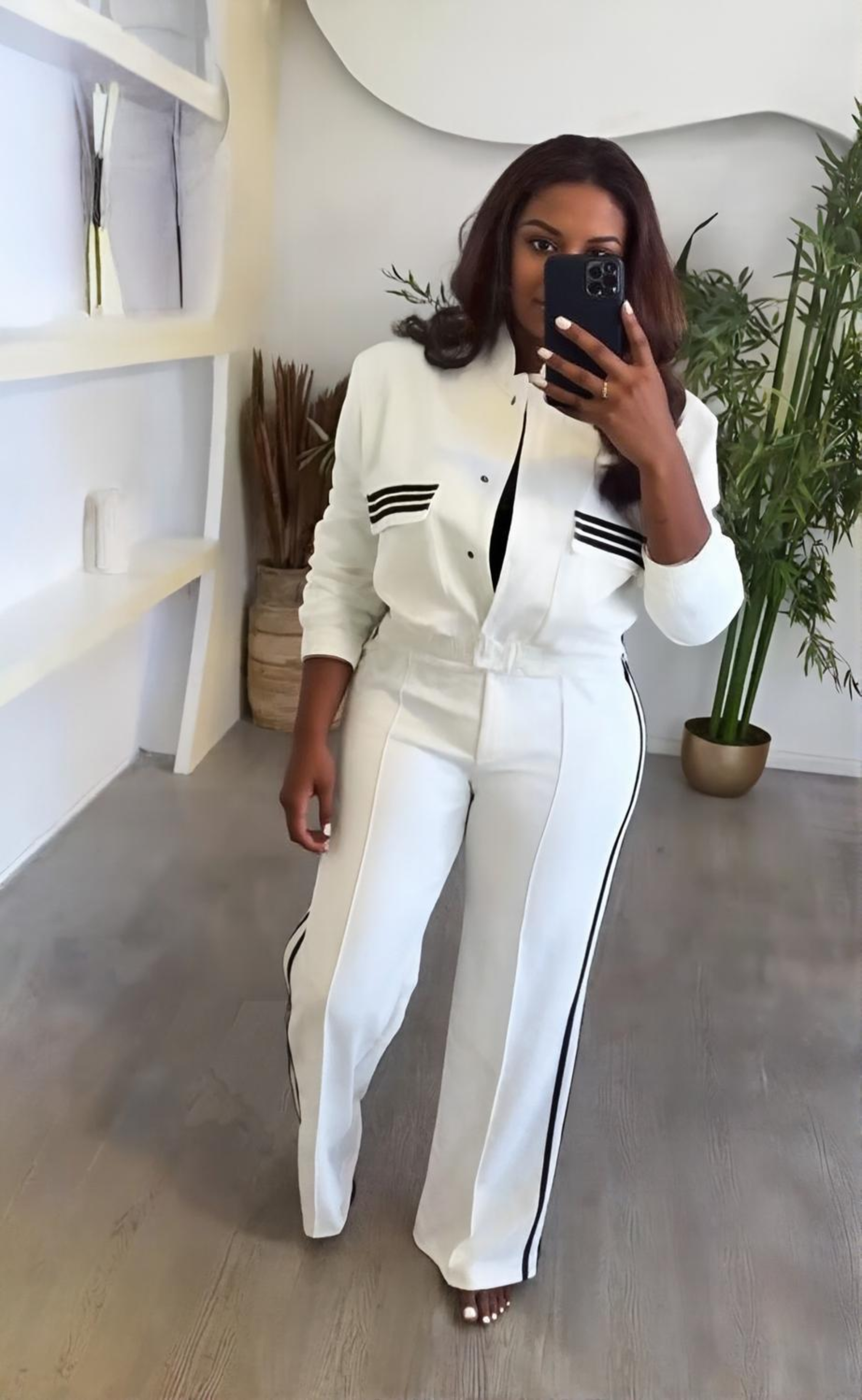 Person wearing a white outfit with black stripes in a modern interior setting.