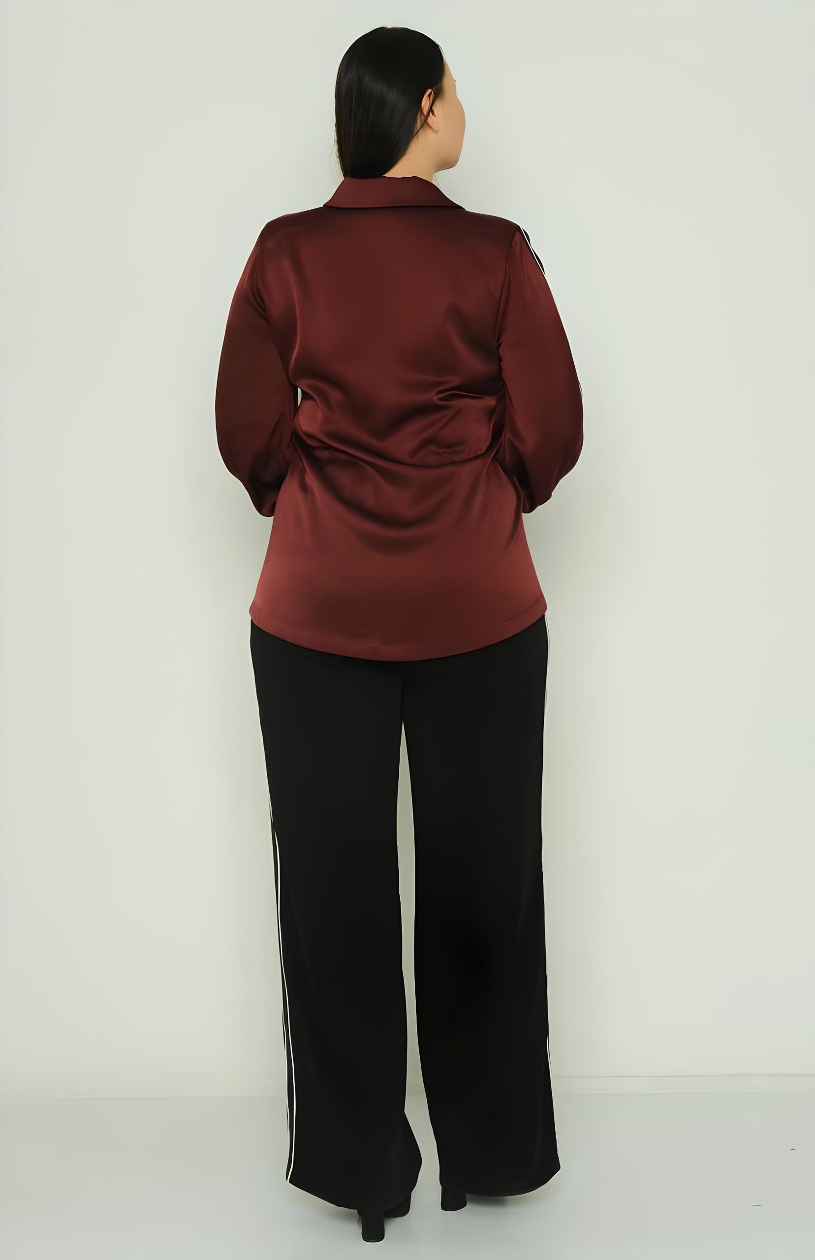 Person wearing a burgundy top and black pants against a white background