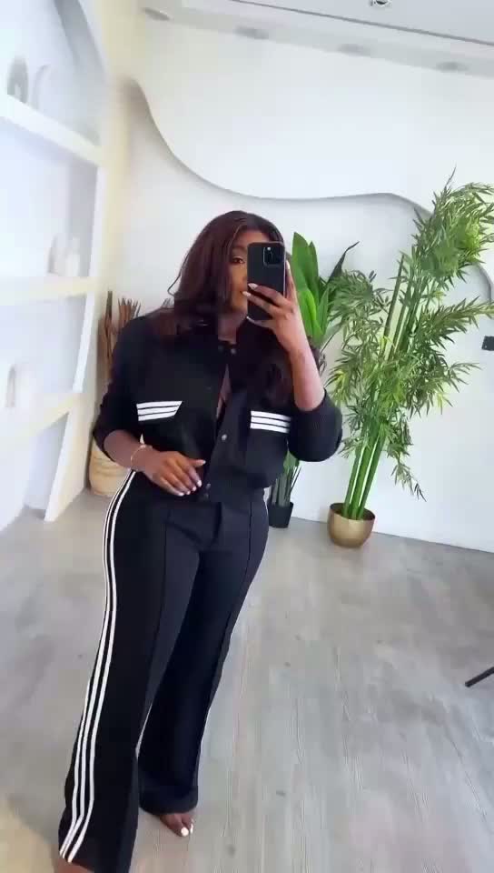 Person wearing a black outfit with white stripes in a room with plants