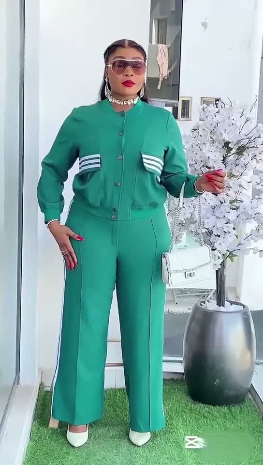 Woman in a green outfit standing in a modern interior setting with decorative elements.