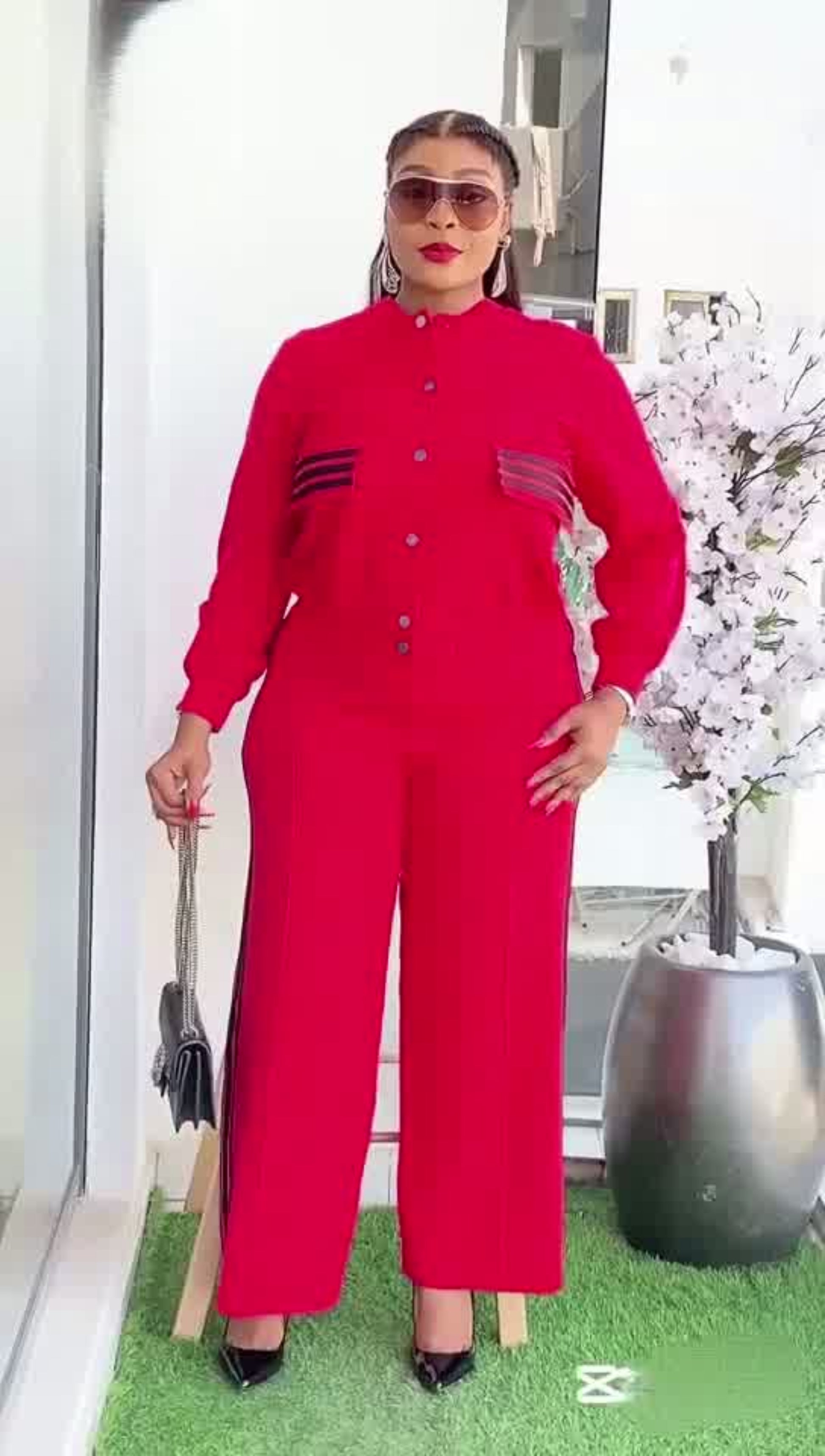 Woman in a red outfit standing outdoors with decorative elements in the background