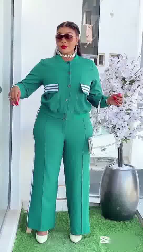 Woman in a green tracksuit standing outdoors with decorative elements in the background