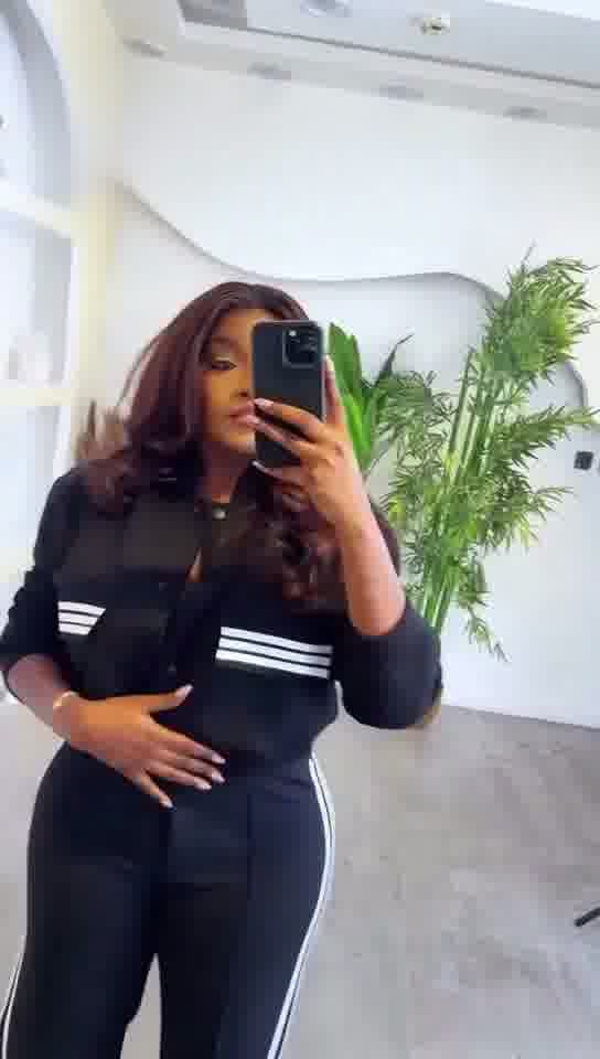 Person wearing a black outfit with white stripes taking a mirror selfie.