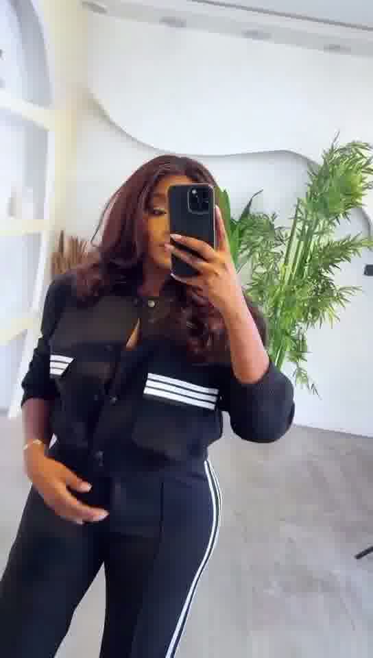 Person taking a mirror selfie wearing a black outfit with white stripes indoors.