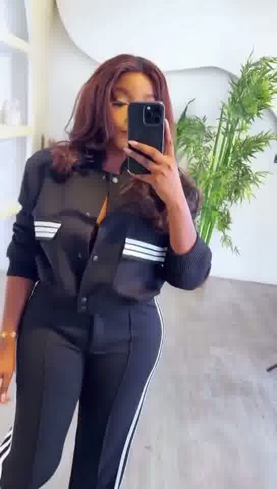 Person wearing a black tracksuit with white stripes, taking a mirror selfie.