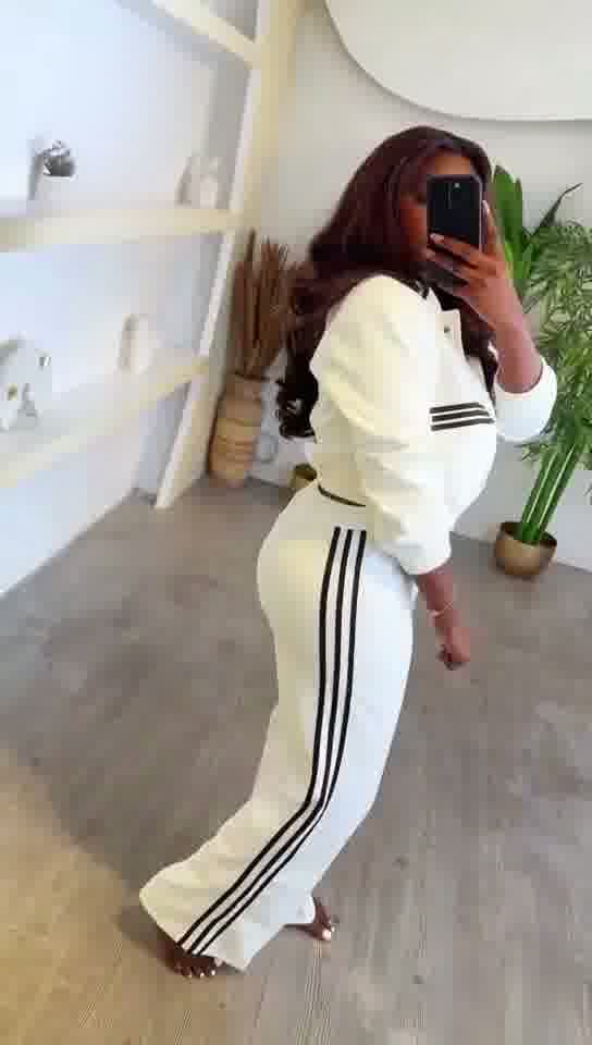 Person wearing a white outfit with black stripes in a room.