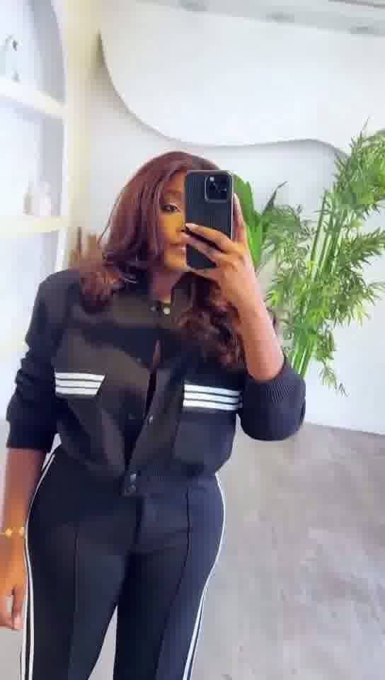 Person wearing a black tracksuit with white stripes in an indoor setting.