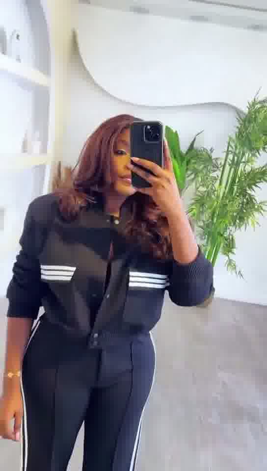 Person wearing a black outfit with white stripes taking a mirror selfie.