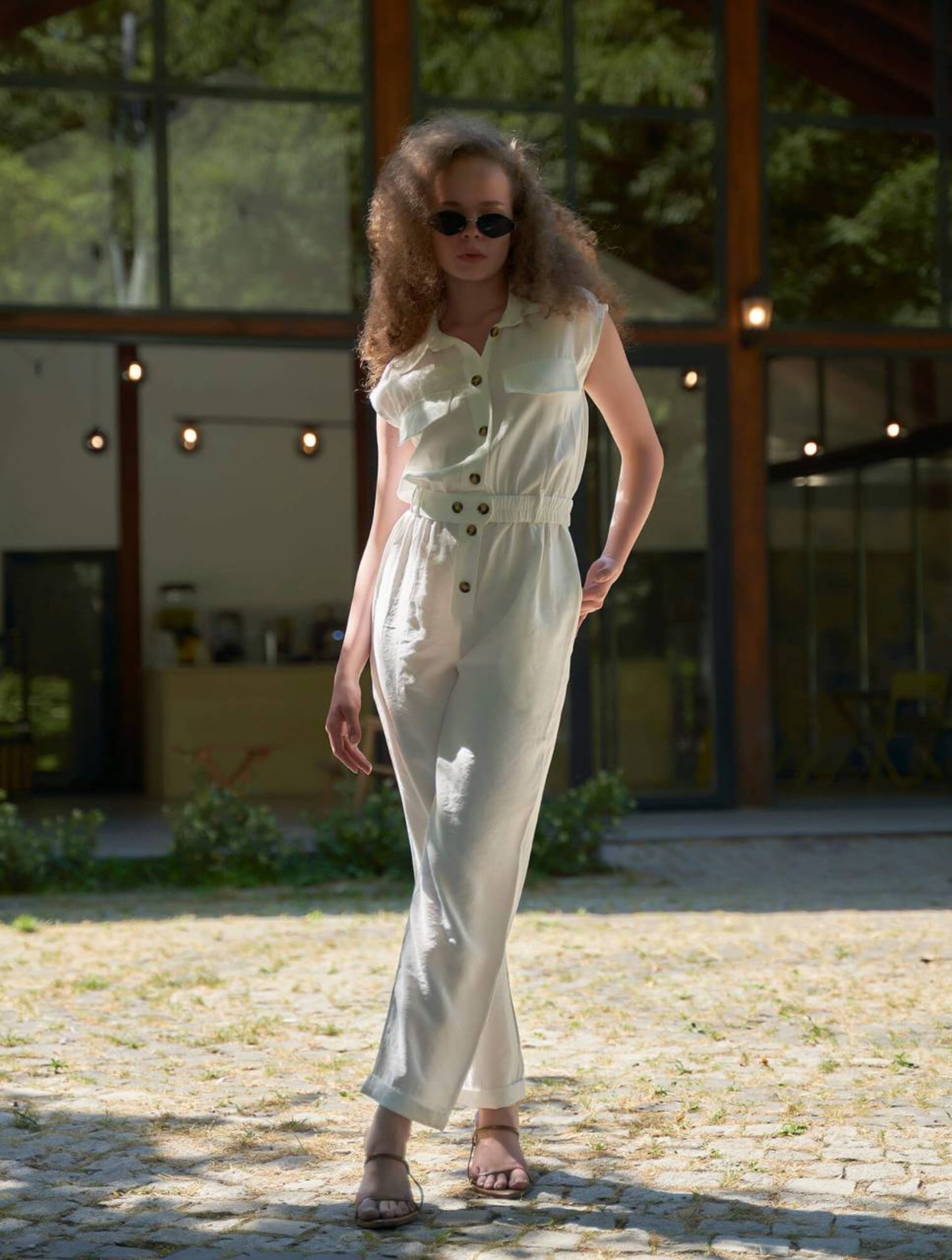 Woman wearing a white outfit with black buttons outdoors.