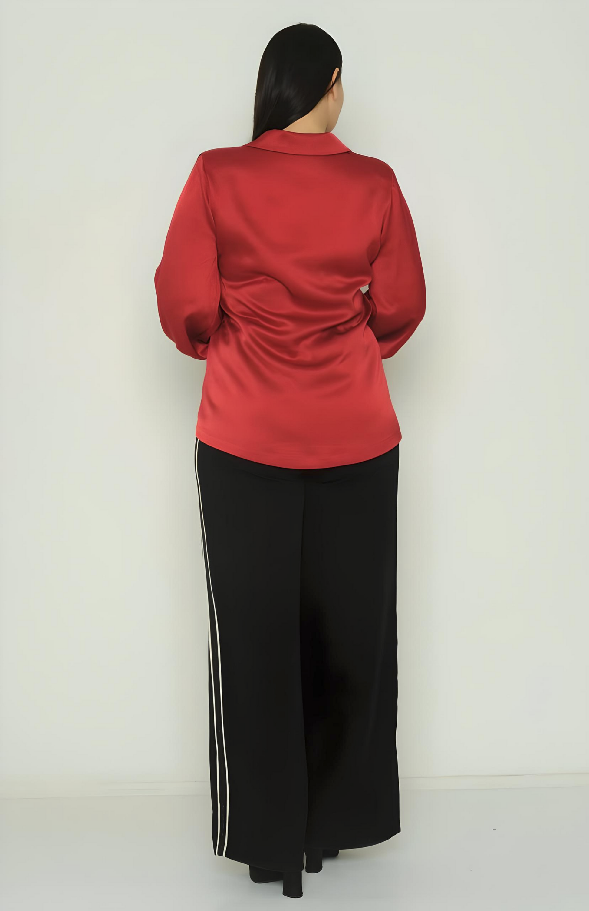 Person wearing a red top and black pants with white stripes on a white background